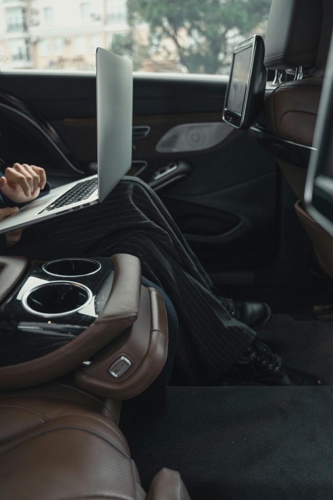 About A professional woman working remotely on a laptop inside a luxurious car. Modern executive lifestyle.