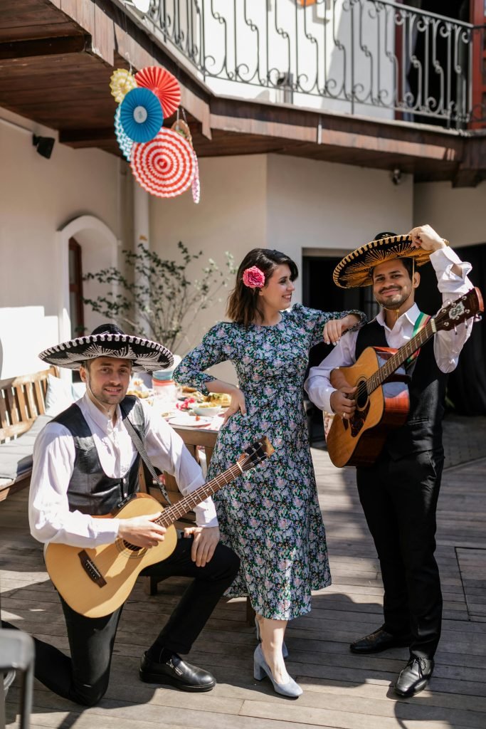 About Group of musicians in traditional Mexican attire with guitars, smiling and posing outdoors.