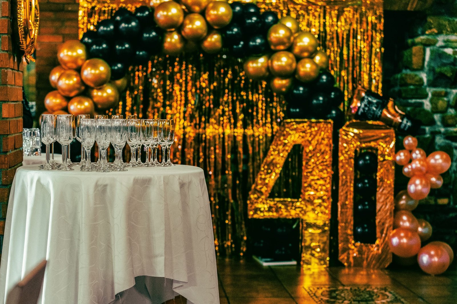 Chic 40th birthday party setting with champagne flutes, balloons, and gold glitter backdrop.
